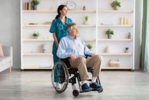 A nurse pushes an older gentleman around on a wheelchair.